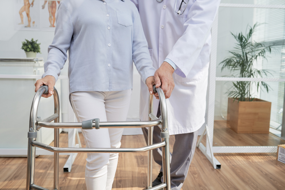 Elderly patient using a walking frame with nurse support during community frailty care